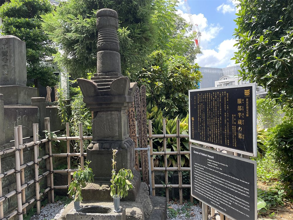 東京都新宿区の西念寺にある服部半蔵の墓。竹の垣根に囲まれた石の宝篋印塔と説明板