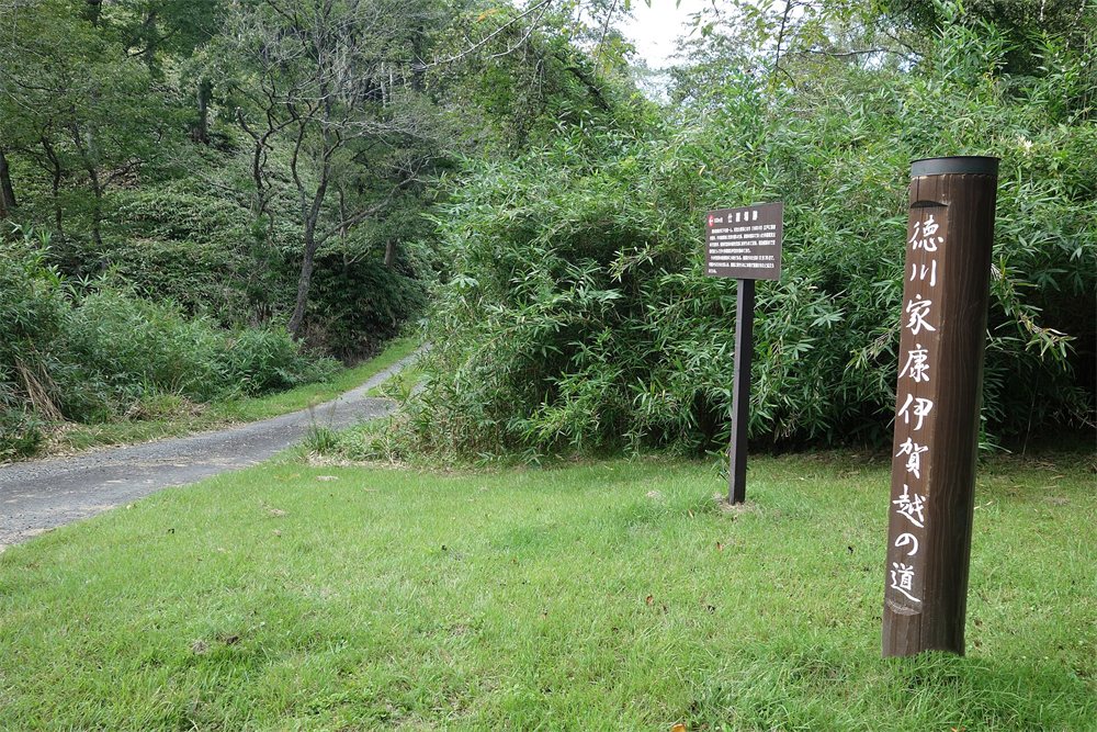 滋賀県甲賀市信楽町の山あいの道と、「徳川家康伊賀越の道」と書かれた木の標柱