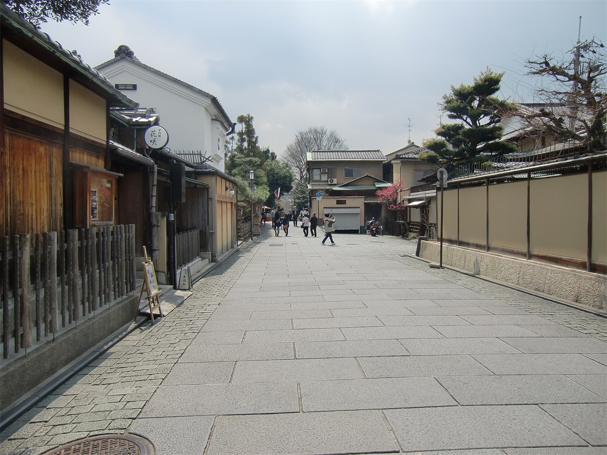 京都・東山のねねの道。白っぽい石畳の広い道の両側に塀と町家が続いている