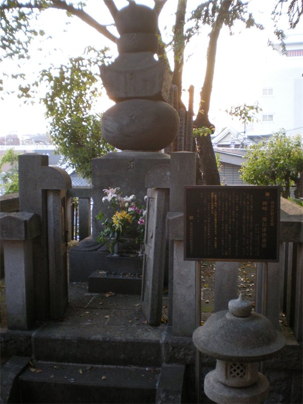 東京都新宿区の西念寺にある松平信康の供養塔。石の柵に囲まれた五輪塔と、新宿区の説明板