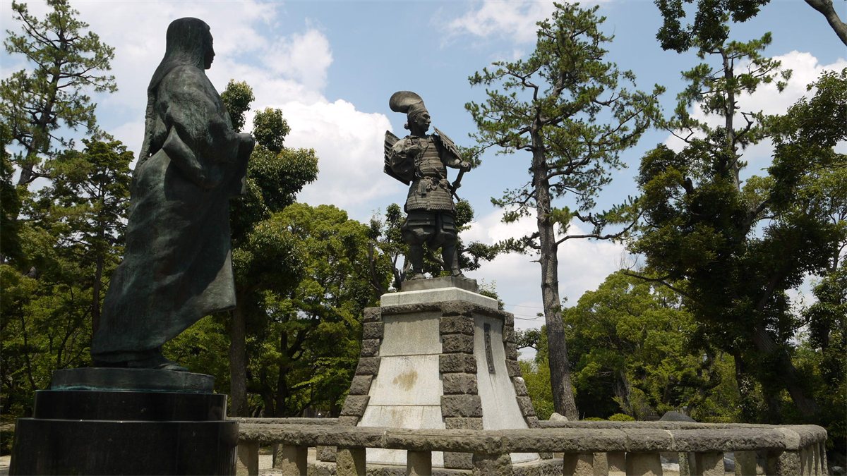 愛知県清須市の清洲公園に立つ濃姫の像と、その先の台座の上に立つ織田信長の像
