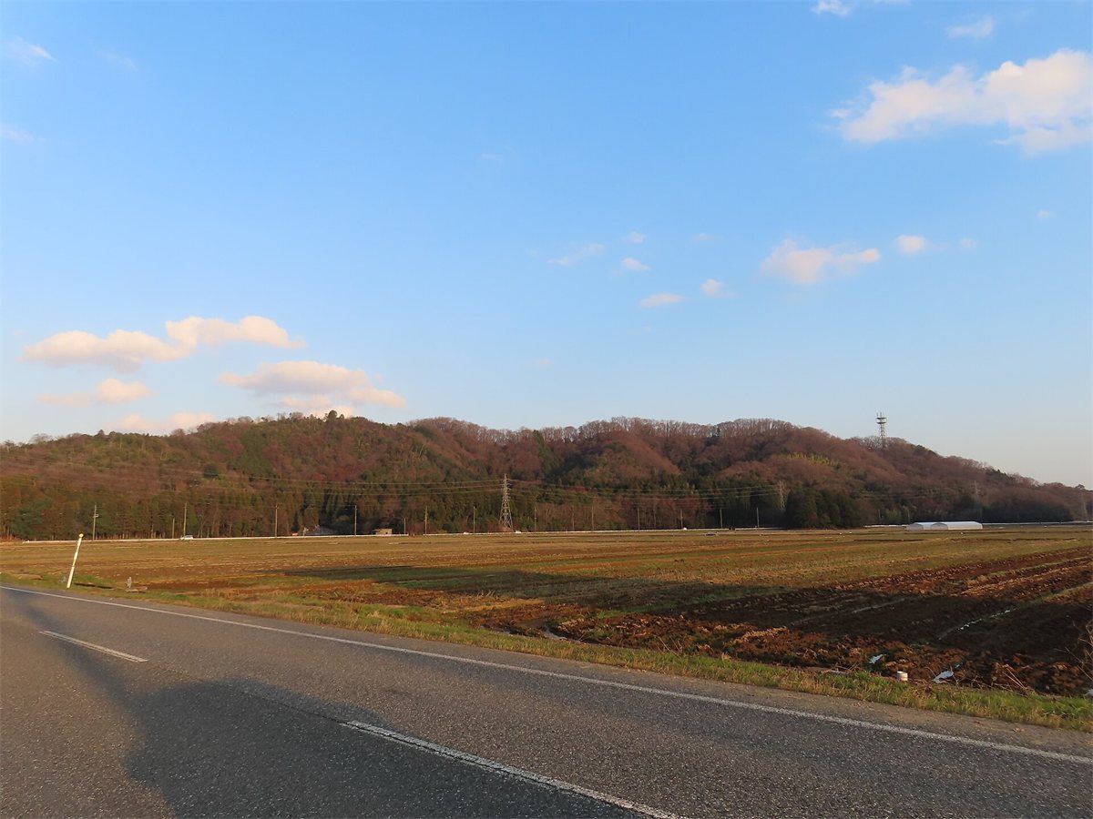 東の道路から見た虎御前山。畑の向こうに、細長く低い山が横たわっている