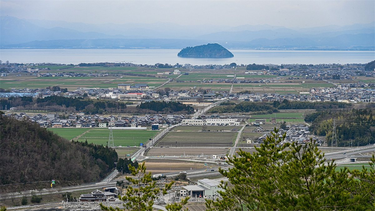 小谷城跡から見下ろした長浜の町と田畑、その先の琵琶湖に浮かぶ竹生島