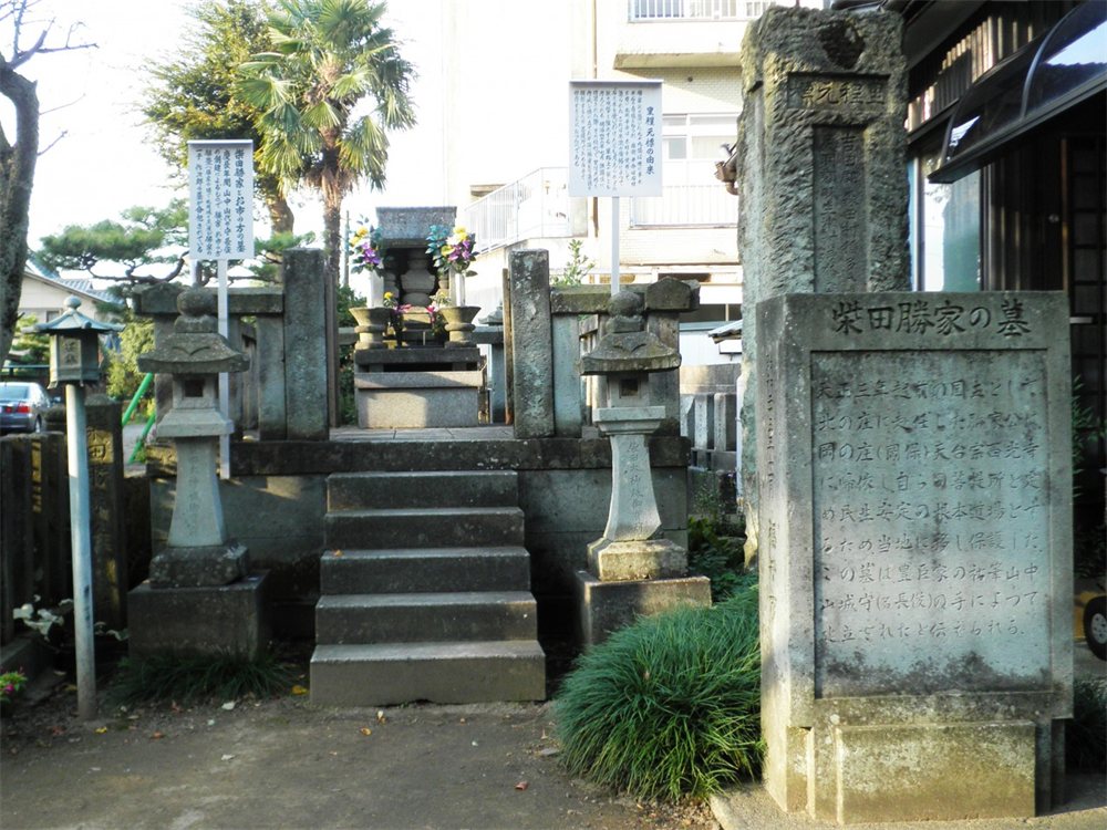 福井市の西光寺にある柴田勝家とお市の方の墓。石段の上に石の塔があり、手前に「柴田勝家の墓」と刻まれた石碑が立つ